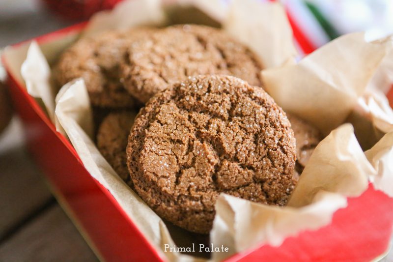 Image shows a close up of gingersnap cookies on tissue paper in a red tin